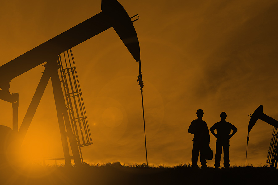 Monochrome photograph of two workers at an oil field